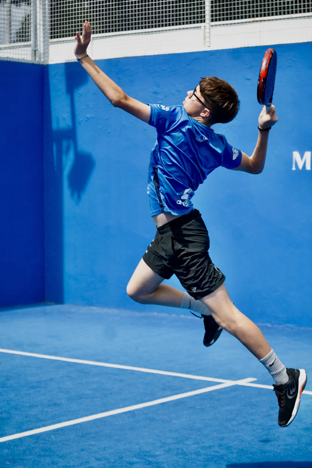 Junior pupil jumping for a smash