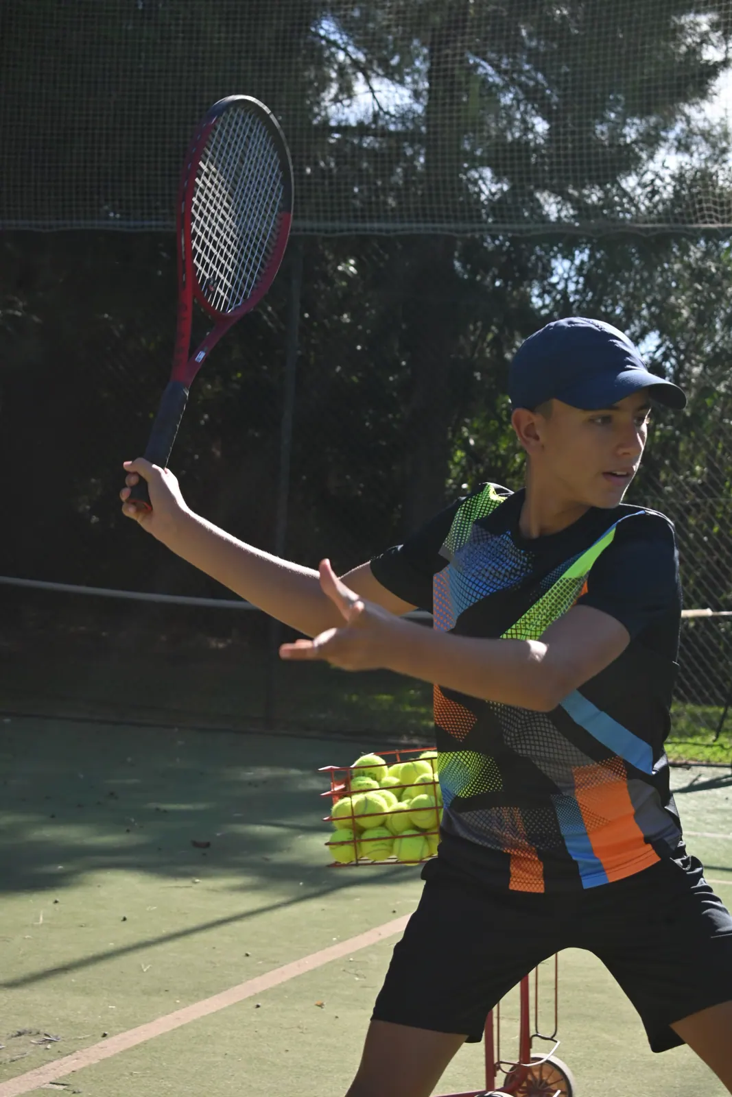 Junior student volleying next to the ball basket