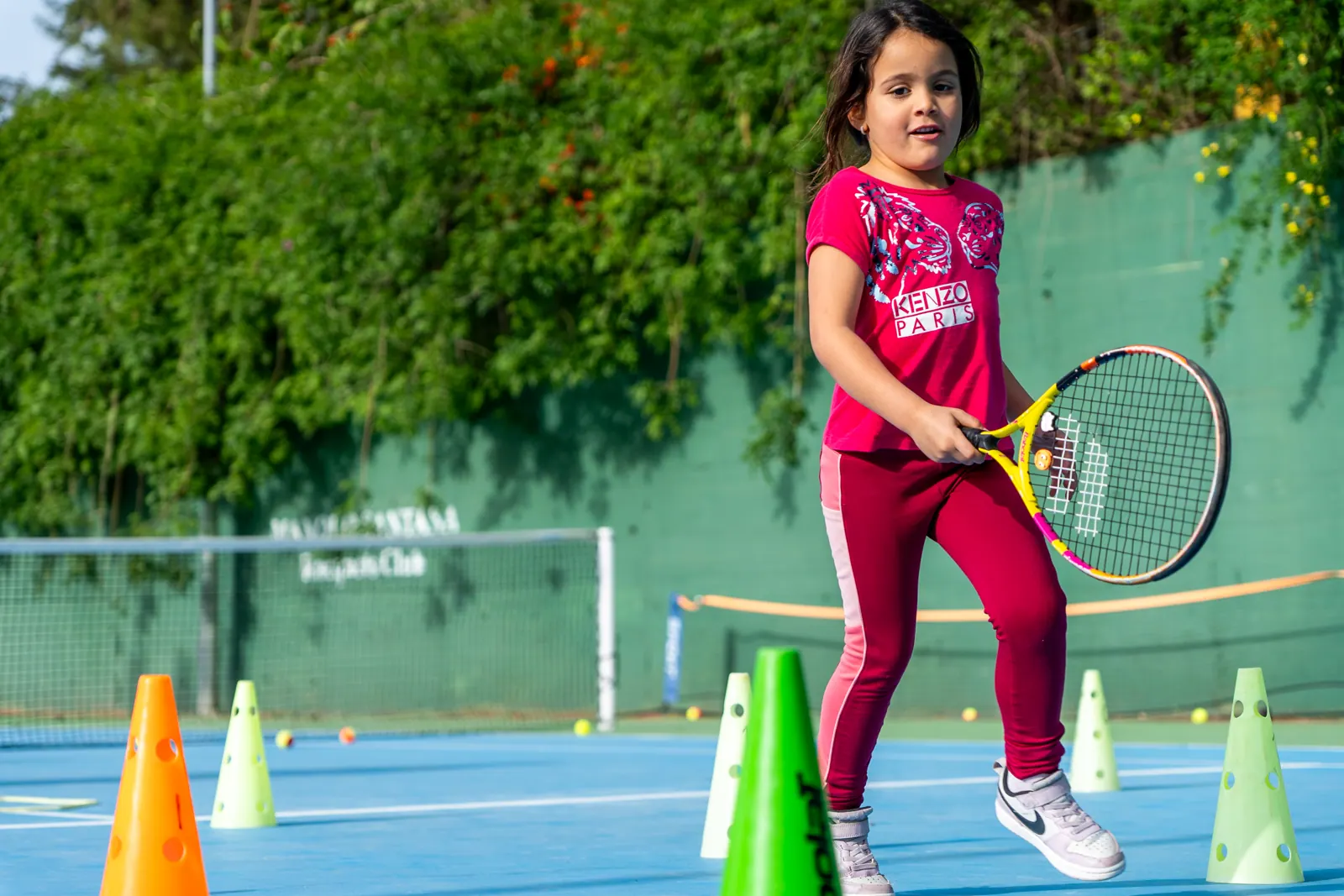 Mini-tennis student among cones on the club court