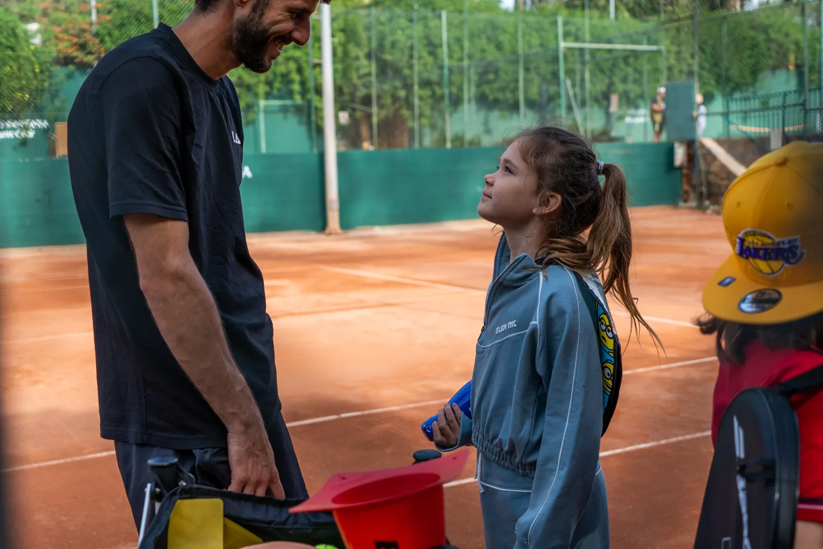 Coach talking with a young student on a clay court