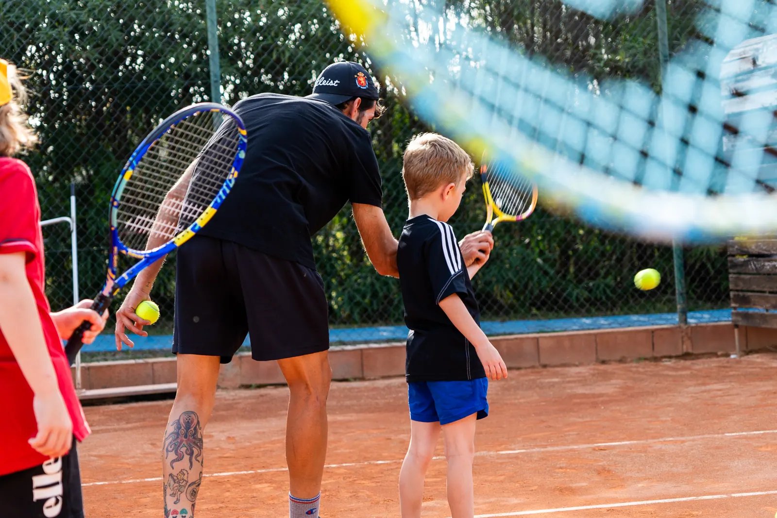 Coach guiding a young student's forehand