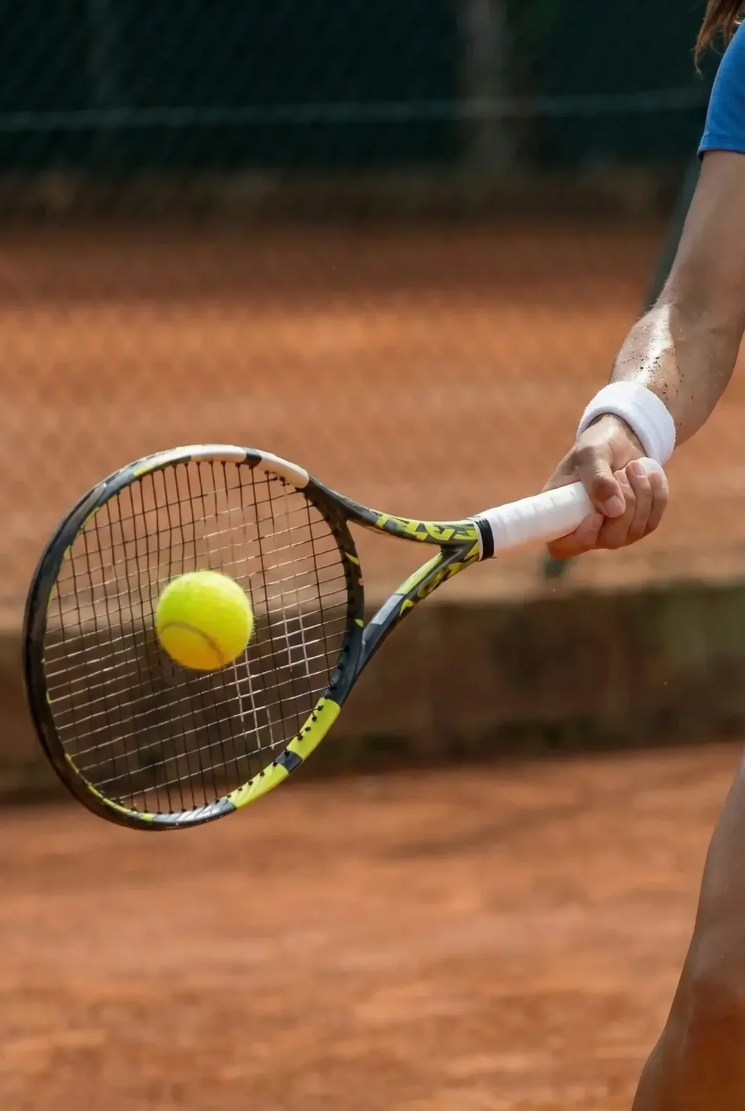 Racket striking the ball over a clay court